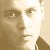 Pixelated close-up of a person's face with visible eyes, nose, and mouth against a light background.