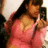 A pixelated image shows a person with long dark hair wearing a pink top, holding an object near their face against a light background.