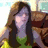 Pixelated image of a person with long dark hair wearing green and black clothing against a blurred background.