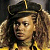 Pixelated static image of a person wearing a dark hat with gold trim and long curly hair, set against a blurred background.