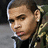 Pixelated image of a person with short hair and an earring, wearing a camouflage-patterned jacket over dark clothing against a blurred background.