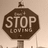 A brown octagonal sign with 'STOP LOVING' text on a pole, displayed in four showing slight variations