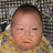 Pixelated close-up of a child's face with closed eyes, wearing a yellow garment against a checkered background.