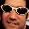 Four identical pixelated images of a person wearing light-colored sunglasses arranged in a with subtle facial expression variations