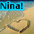 A pixelated image shows a blue banner with black text reading "Nina!" above a heart drawn in sand on a beach with waves in the background.