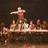 A four- shows a stage performance with dancers, text , and black-and-white photo strips