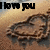 A heart-shaped sand drawing on a beach with 'I love you' text above it, showing subtle animation changes in the heart's outline and background lighting.