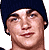 Pixelated static image of a person's face with dark hair, visible facial features including eyes, nose, mouth, and skin tone, set against a white background.