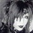 A low-resolution grayscale static icon featuring a stylized face with dark hair and light skin tones, partially obscured by pixelation.