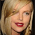 Pixelated close-up of a person with light brown hair, red lips, and a black garment visible at the bottom edge.