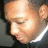Pixelated close-up of a person's face with closed eyes, light skin tone, and visible ear, set against a dark background with a bright light source on the right.