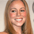 Pixelated close-up of a smiling person with long light brown hair against a light background.