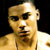 Pixelated close-up of a person with light skin tone, dark eyes, and short dark hair, wearing a white sleeveless top against a dark background.