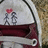Two stylized figures stand on a red platform beneath a pink heart, set against a light gray background with a curved dark line.