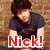 Pixelated image of a person with dark hair wearing a dark shirt, standing against a brown textured background with red text reading "Nick!" at the bottom.