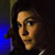 Pixelated close-up of a person's face with dark hair, blue background light, and dark clothing visible.