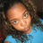 Pixelated close-up of a person with light skin tone wearing blue clothing against dark background.