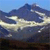 Pixelated landscape with blue sky, dark mountain peaks, and light horizontal bands across the middle, rendered in low-resolution style.