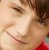 Pixelated close-up of a person's face with closed eyes, brown hair, and red clothing visible at the bottom right.