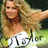 Pixelated image of a person with long light brown hair wearing a white top, extending an arm outward against a green and dark background with visible text below.