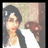 Pixelated image of a person with dark hair wearing a white top and black jacket, holding a brown object against a light background.