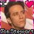 Pixelated portrait of a person with light skin tone, brown hair, and closed eyes; pink heart symbol in top-right corner; text "Jon Stewart" at bottom.