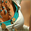 A close-up of a person wearing turquoise and gold jewelry, including large circular earrings and a headpiece with blue gemstones.