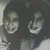 Two pixelated faces with dark hair and light skin, both smiling broadly against a muted background.