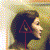 Pixelated profile of a person with dark hair holding a red triangular symbol against a blurred background with light and dark tones.