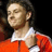 Pixelated static image of a person in an orange outfit with white collar against dark background