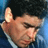 Pixelated close-up of a person's face with visible ear and partial hair, set against dark background with blue gradient edges.