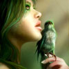 A close-up of a person with green hair holding a small green bird on a finger, set against a blurred background.