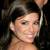 A pixelated close-up of a person with dark hair, light skin, and a neutral expression, wearing a thin strap over the shoulder.