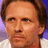 Pixelated image of a person with brown hair and light skin wearing a white shirt, next to blue pixelated text on a light background.