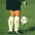 Pixelated static image of a soccer player's lower body on green grass with a white ball nearby.