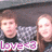 Two people stand side-by-side against a dark background with a light patterned lower section; text at bottom reads "Love<3" in purple and white.