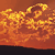 A static pixelated image of a fiery orange and yellow abstract shape against a dark brown background with a black lower border.
