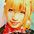 Pixelated static image of a smiling character with blonde hair and red clothing against a light background.