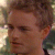 Static pixelated image of a person's face with brown hair, visible ear, and blurred background with light and dark tones.