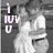 Pixelated grayscale image with light pink text 'i LUV U' on left, two figures in white and dark clothing embracing against a gray background.