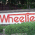 Pixelated red text reading 'Wheelie' on a white background with green and dark pixelated areas above and below.