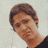 Static pixelated image of a person's head and upper neck with brown hair, light skin tone, visible facial features including eyes, nose, mouth, and ear, wearing dark clothing against a plain background.