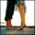 Two human legs in dark pants and brown shoes stand on a blue-tiled floor against a white background.