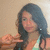 Pixelated image of a person with long dark hair wearing a light-colored top, holding an object in their right hand against a beige background.