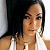 Static pixelated image of a person with long dark hair wearing a white sleeveless top, cropped to show upper body and face against a light background.