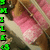 A pixelated image shows a person in pink clothing with green text on the left side, set against a blurred background.