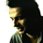 Pixelated profile view of a person with dark hair wearing a greenish garment against a white background.