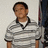 Pixelated image of a person wearing a gray and white striped polo shirt with dark collar trim, standing against a light background.