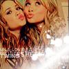 Two women with long wavy hair pose closely together, both blowing kisses with lips puckered and eyes looking upward.