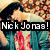 Pixelated image of a person with dark hair and light skin wearing a white top and blue jacket, overlaid with bold text reading "Nick Jonas!" in white letters on a black bar.